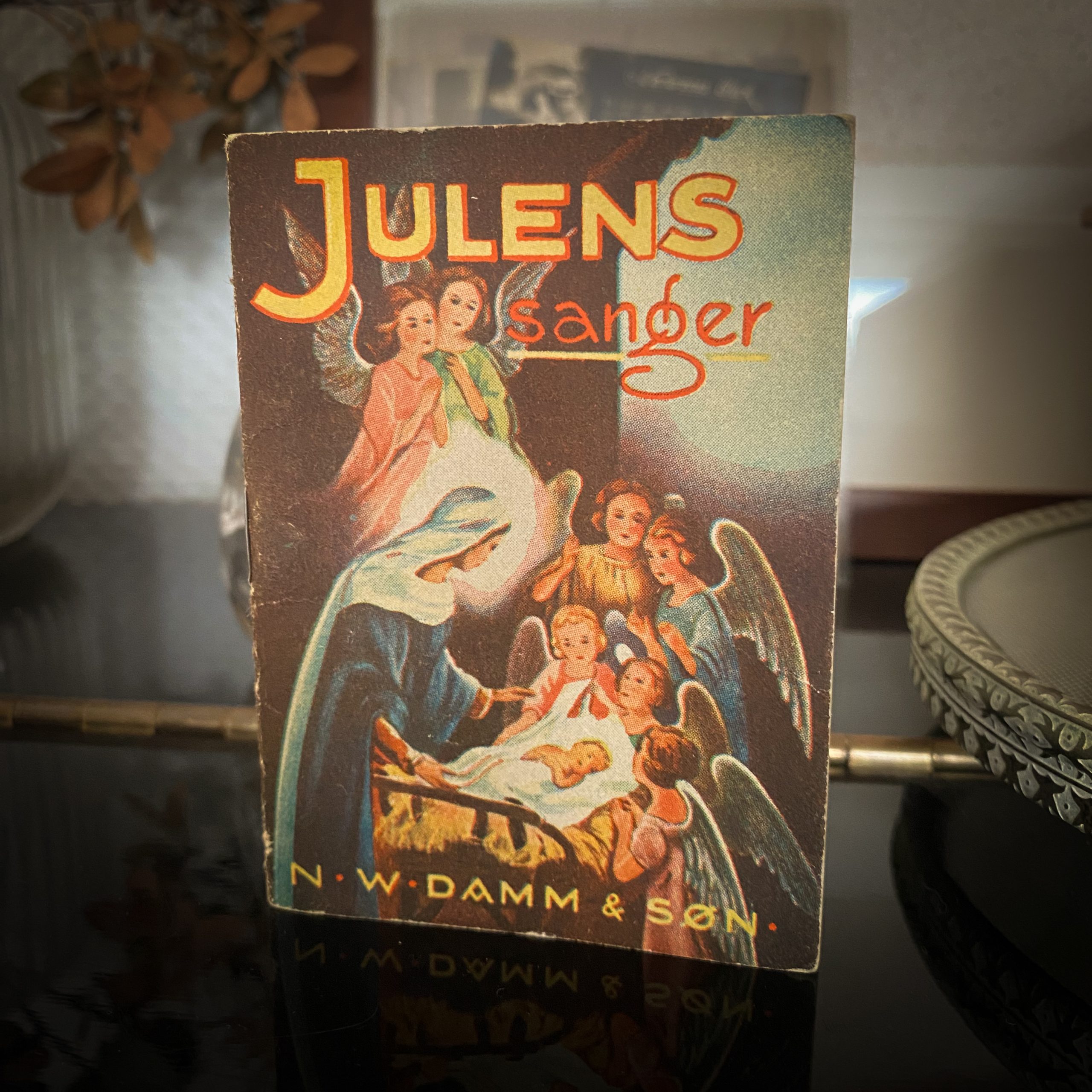 Et gammelt hefte med tittelen «Julens sanger» fra N.W. Damm & Søn, illustrert med engler og Maria ved krybben.